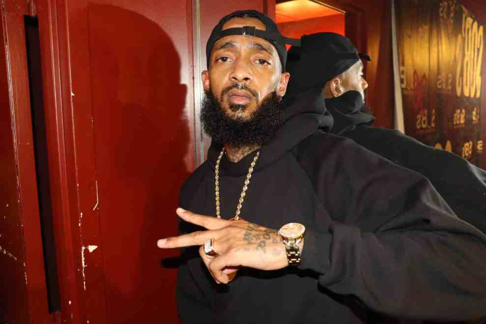 Nipsey Hussle wearing all black throwing up the peace sign