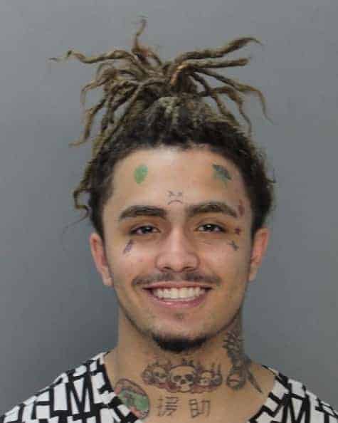 Lil Pump  with hair up smiling in front of gray background