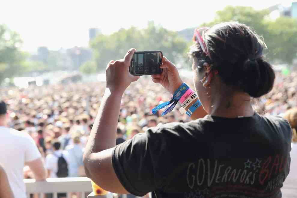 women taking cell phone picture of crowd in Govenors Ball T-shirt