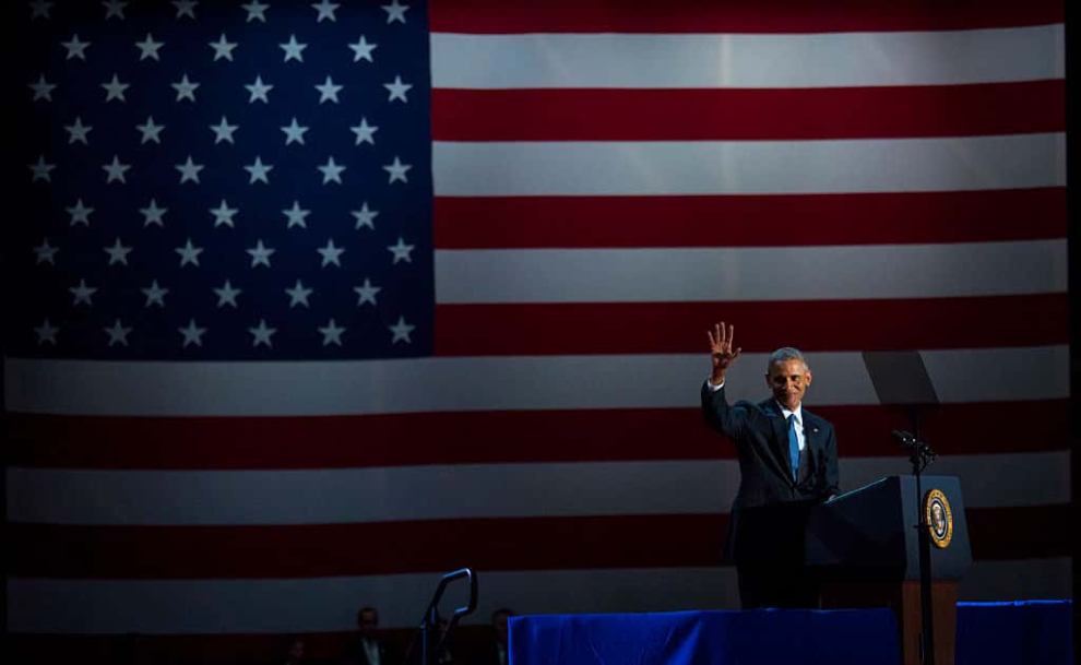 President Obama waving from podium in front of American Flag