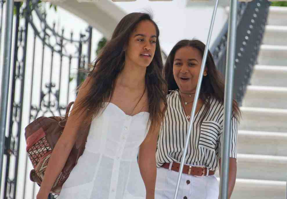 Malia Obama in white dress and Sasha Obama in black and white striped shirt and white skirt