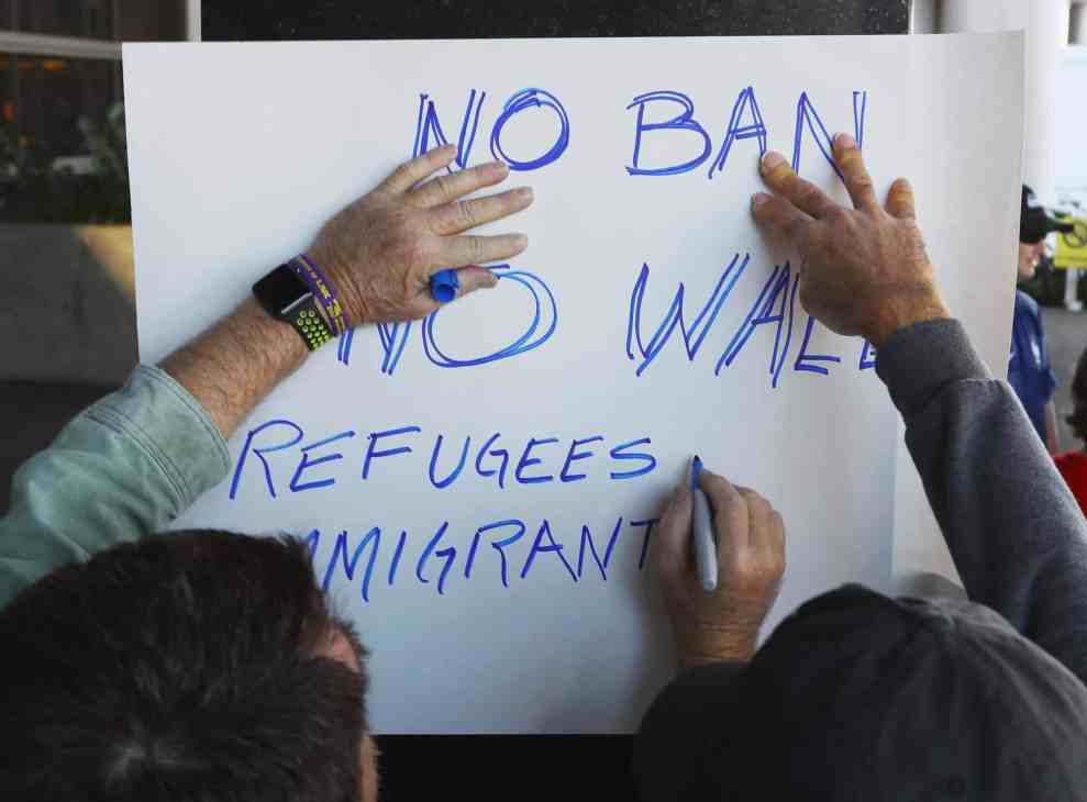 handwritten sign reading "No Ban No Wall Refugees Immigrants"