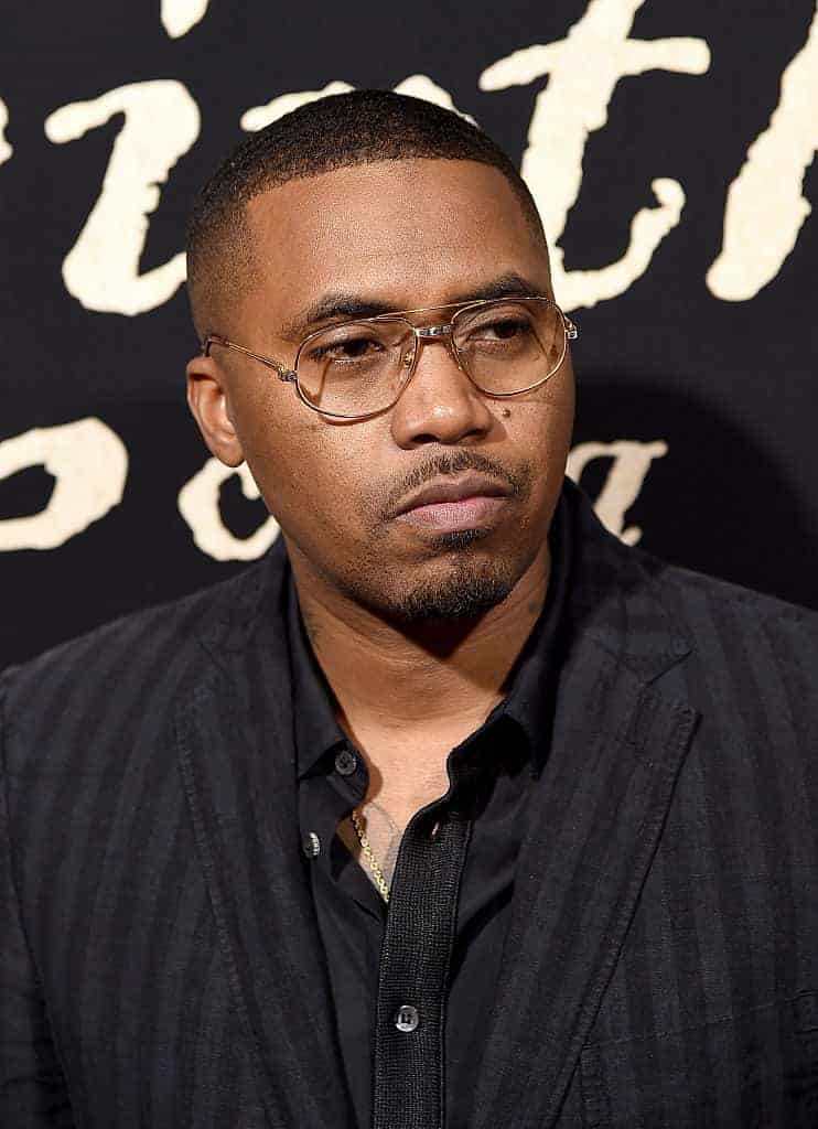 Nas in glasses and black shirt and jacket