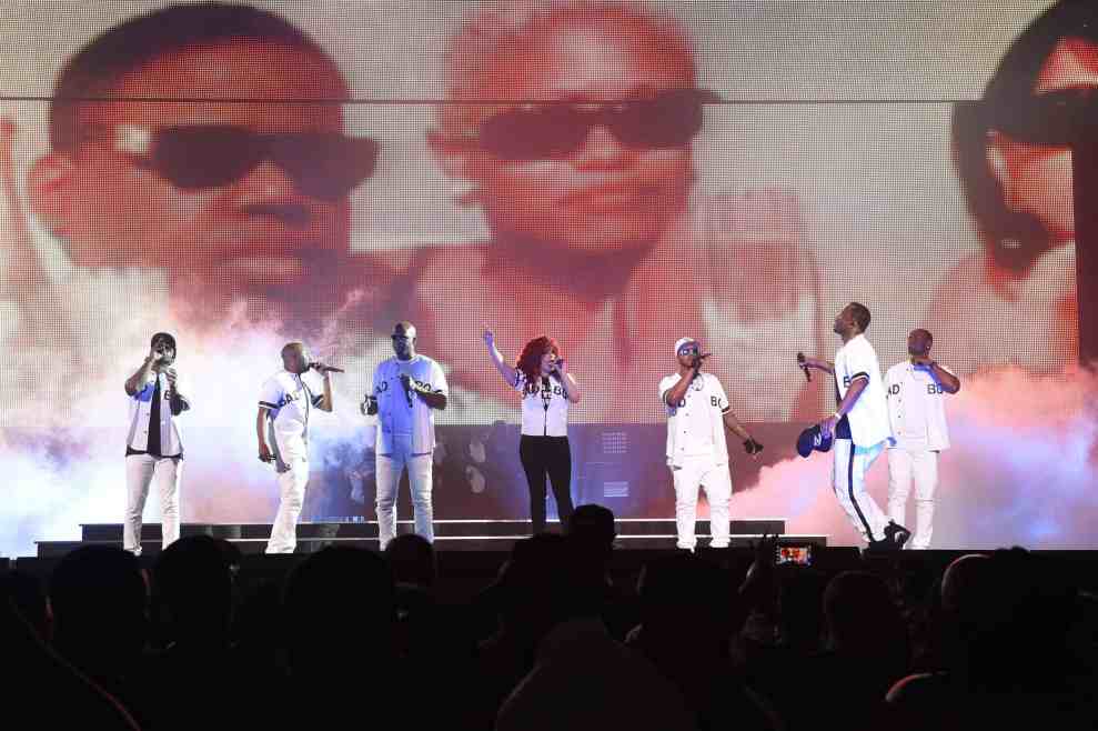 Faith Evans and others in Bad Boy jerseys in front of screen of Biggie