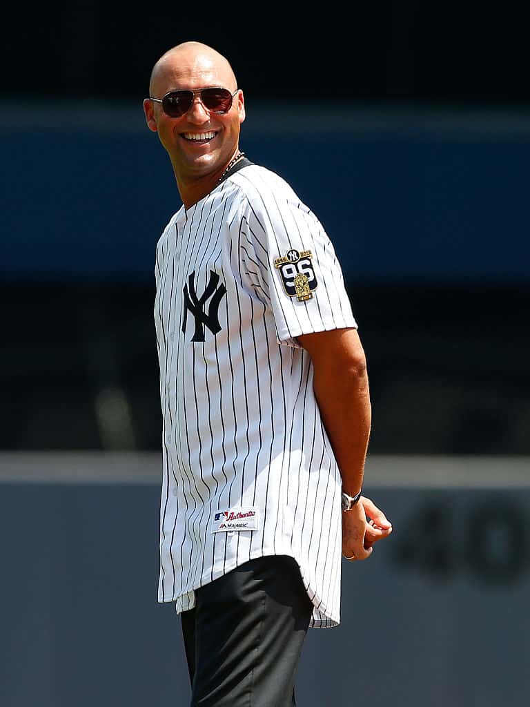 Derek Jeter in Yankees jersey and sunglasses with hands clasped behind his back