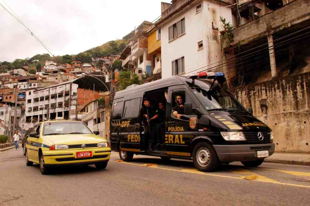 Brazilian police vehicle and passenger cars going down the street