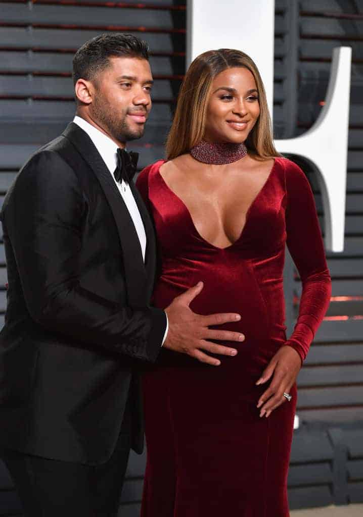 Russell Wilson with hand on belly of pregnant Ciara