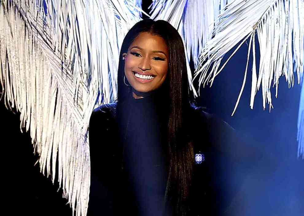 Nicki Minaj in front of blue background with white palms