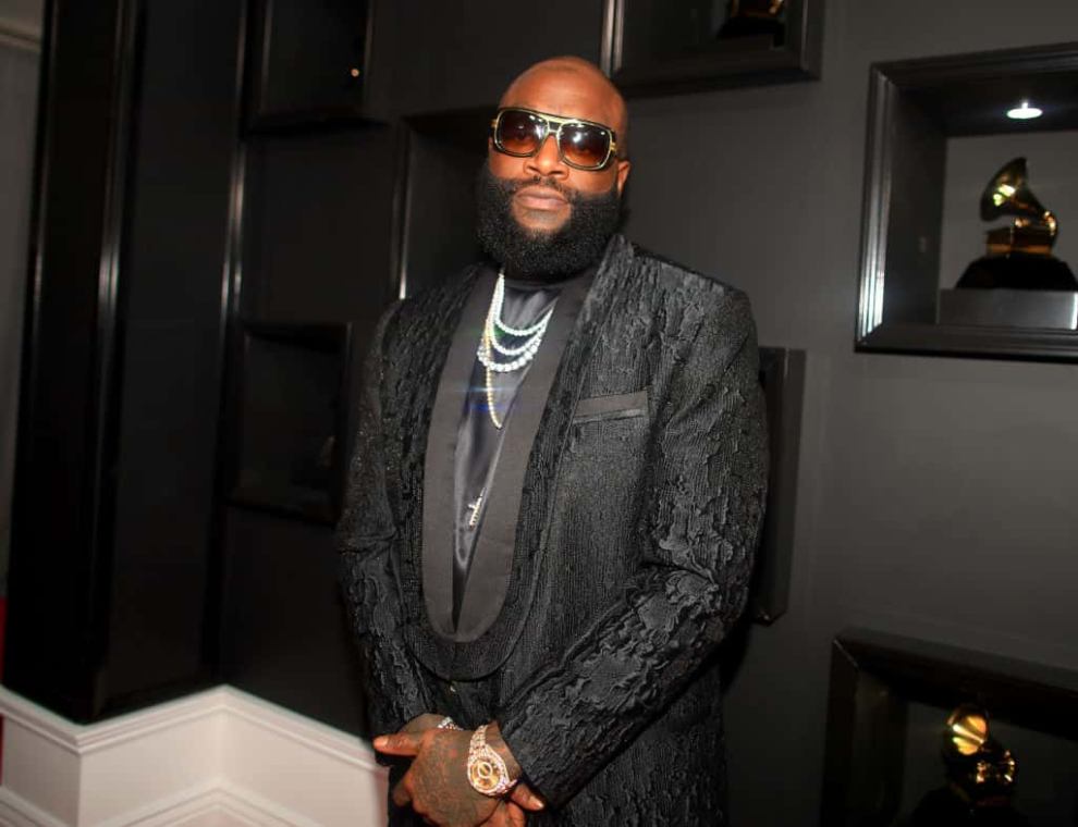 Rick Ross in front of wall of awards