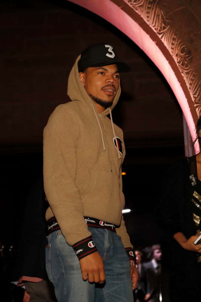 Chance the Rapper performing in black baseball cap reading 3 and tan champion hoodie