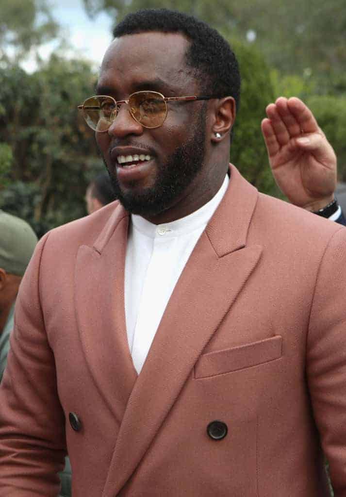 Diddy in long pink formal jacket over white shirt outdoors