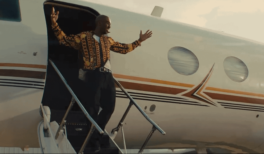 2Pac exiting plane with both arms raised above head