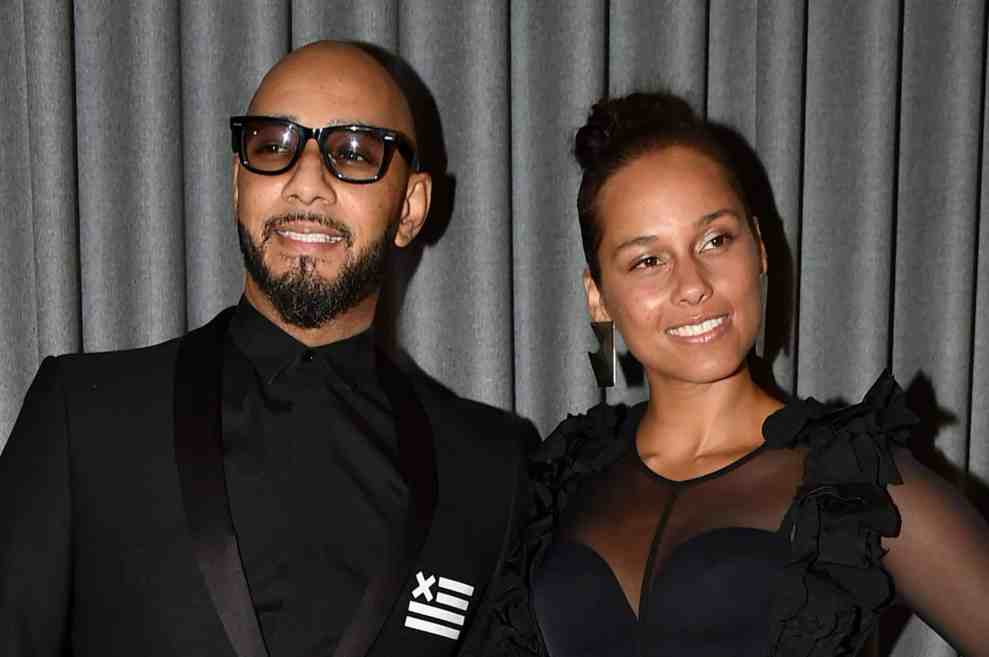 Swizz Beatz and Alicia Keys at event in front of gray fabric background
