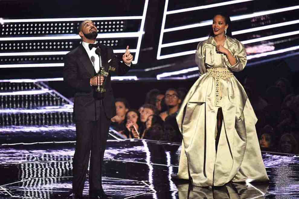 Drake with MTV Moonman statue pointing up sharing stage with Rihanna