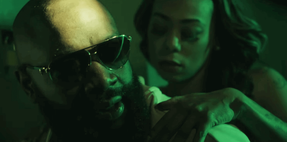 Still of Rick Ross from video in bed with girl under green light