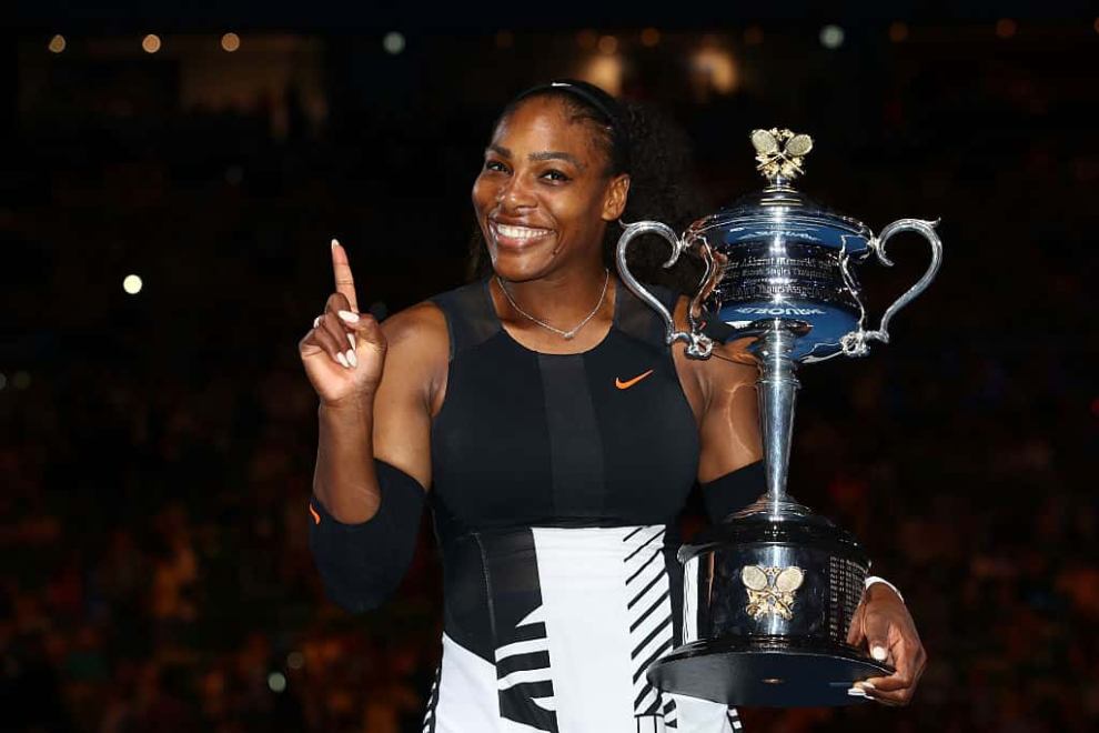 Serena holding Australian Open tennis trophy and pointing her finger in a #1 position