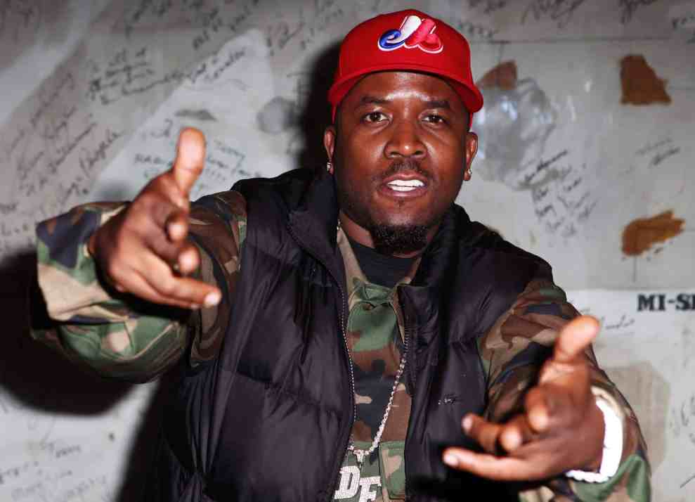 Big Boi posing in front of wall of autographs