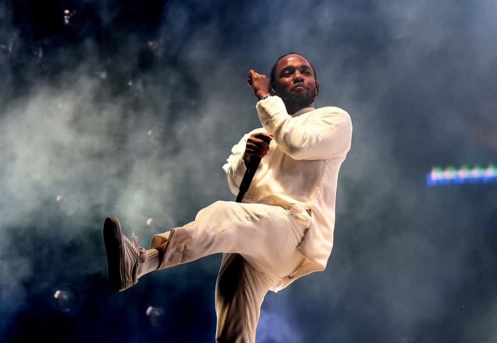 Kendrick Lamar performing in all white against smoky background