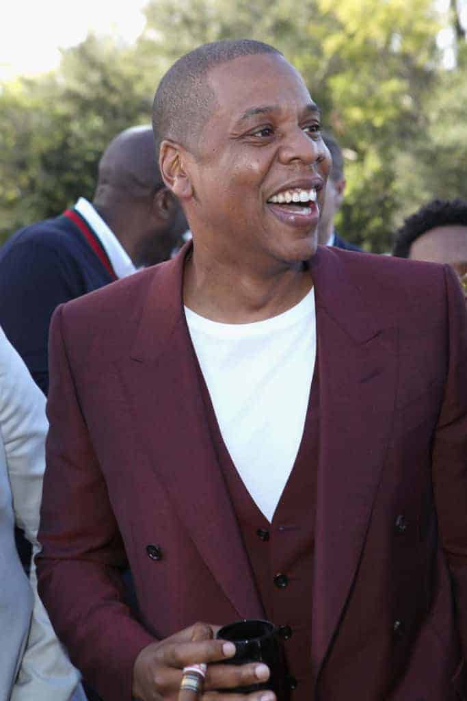 Jay Z in maroon jacket smiling outside
