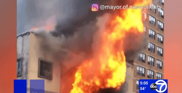 Screenshot from video of private jet crashing in New Jersey with large fire in front of multi-story building