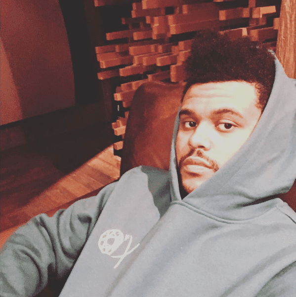 The Weeknd lounging in gray hoodie