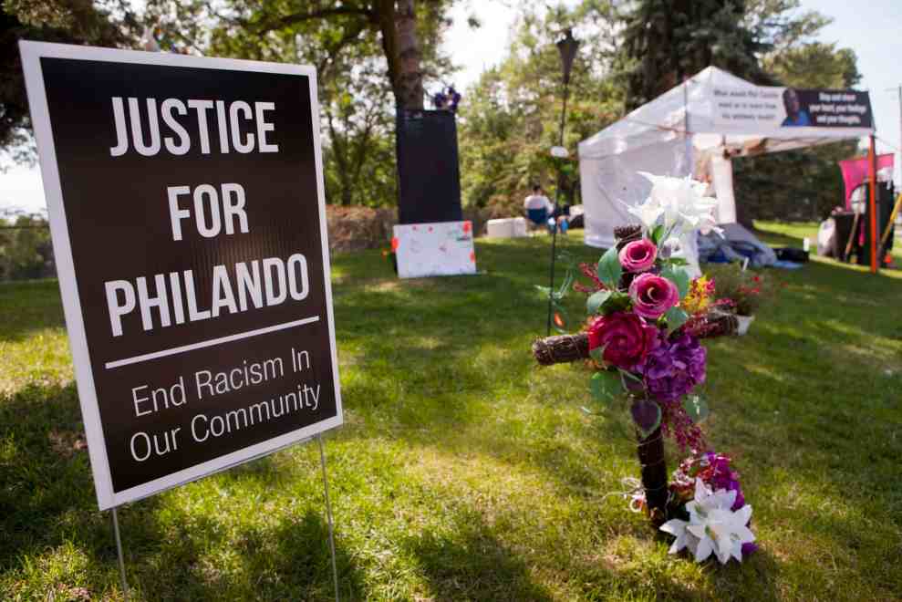 Sign "Justice for Philando : End Racism in Our Community" next to wooden cross with flowers