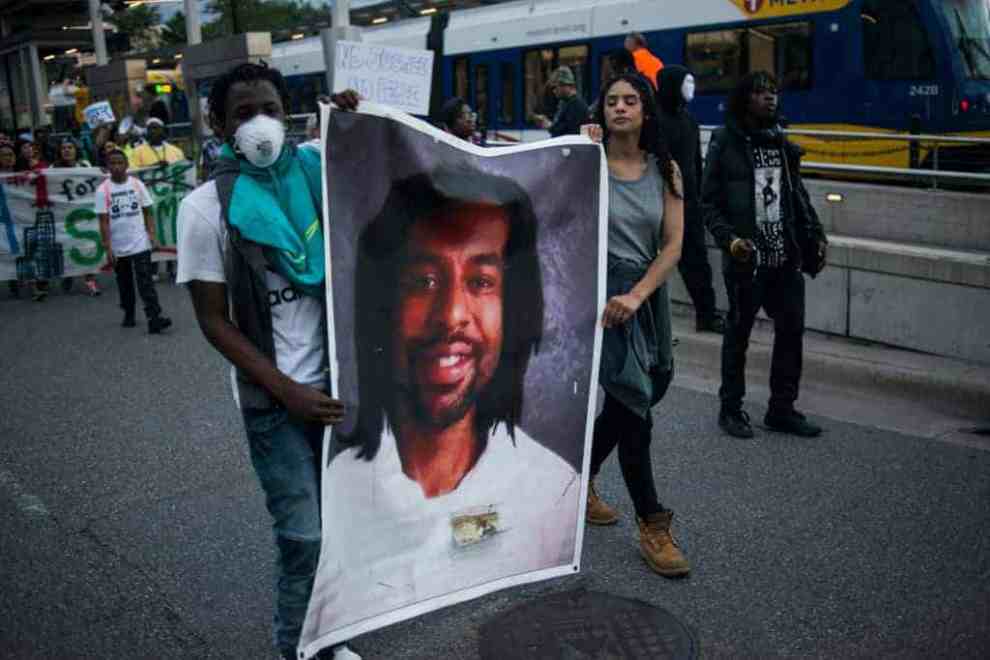 Protest marchers holding an enlared photo banner of Philando Castile