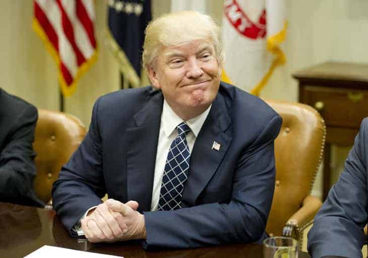 Trump smiling while sitting at conference table