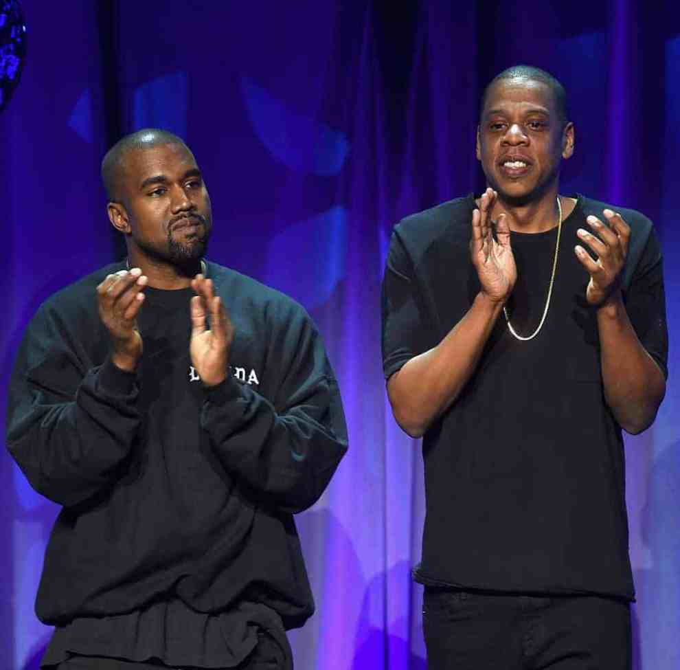 Kanye West and Jay Z clapping in front of blue background
