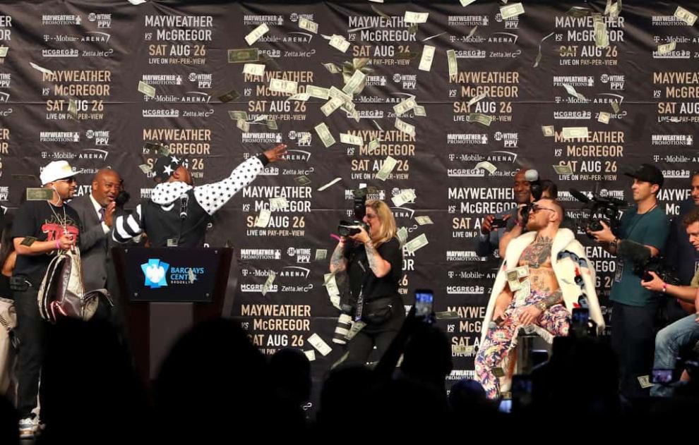 Floyd Mayweather Jr. throws money in the air over Conor McGregor during the World Press Tour event at Barclays Center July 2017