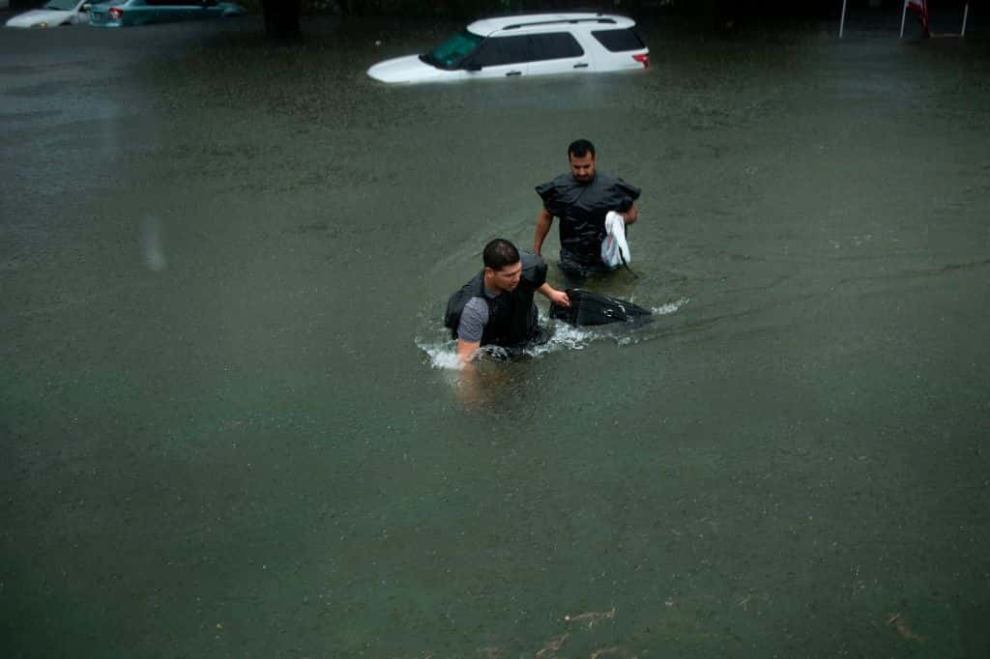 People dragging suitcase through flooded streets as the effects of Hurricane Harvey are seen August 27