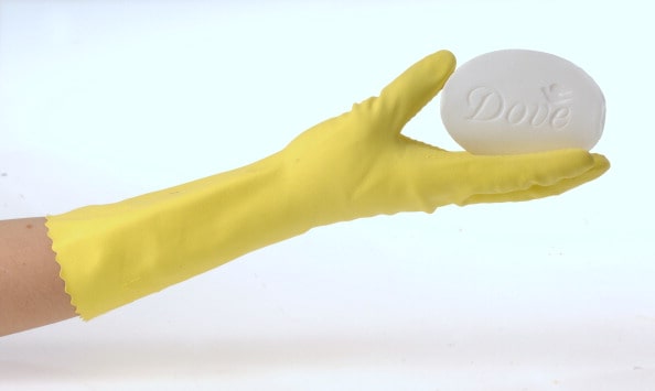 Yellow rubber glove holding a bar of Dove soap