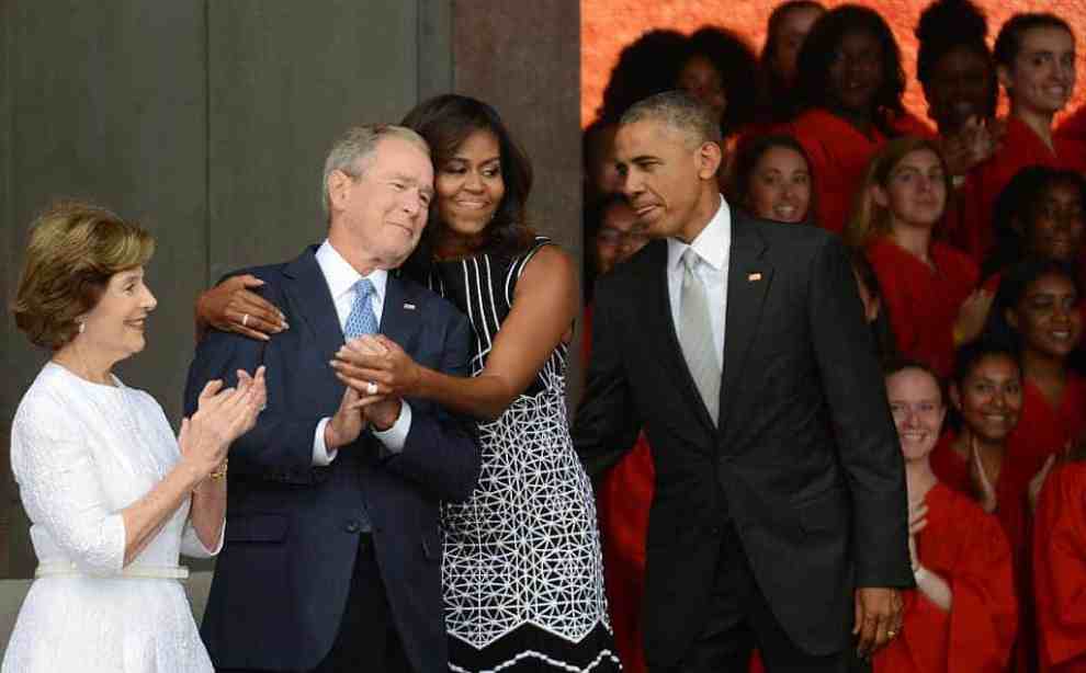 Barak Obama watches Michelle Obama embracing George Bush joined by Laura at Nat. Museum of African American History & Culture