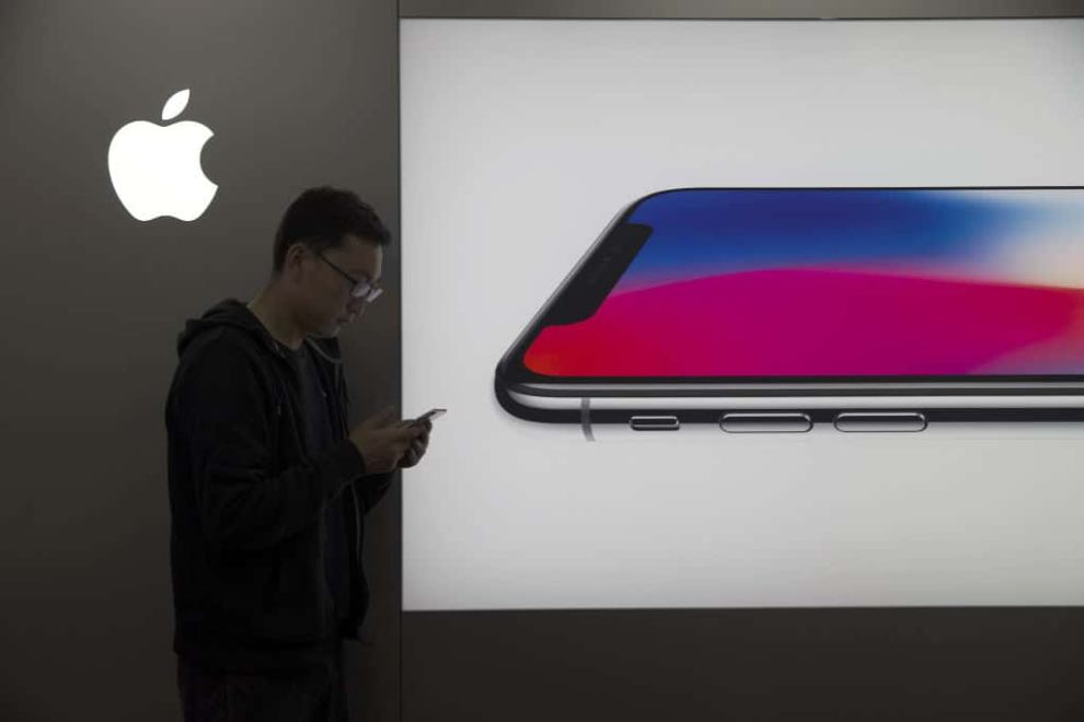 man using iPhone against Apple iPhone advertisement