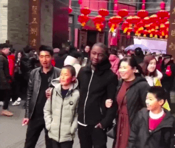 Screenshot from video of black man posing with Chinese family in China