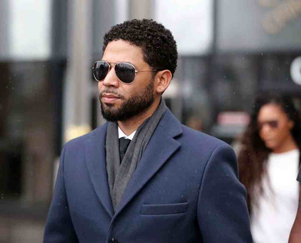 Jussie Smollett wearing a grey suit and sunglasses
