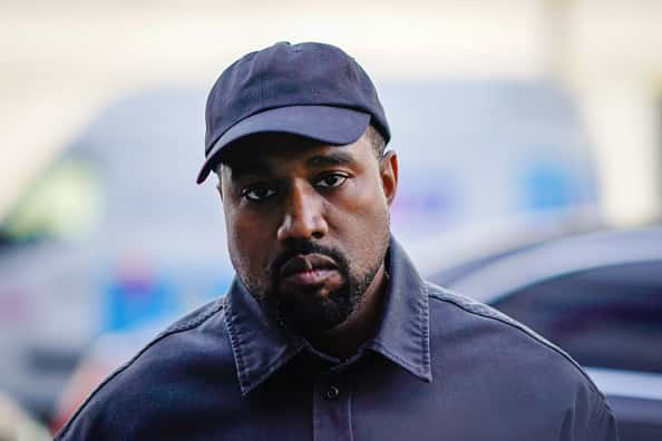 Kanye West in black baseball cap and black button down shirt