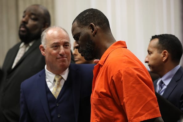 Singer R. Kelly appears standing beside his attorney