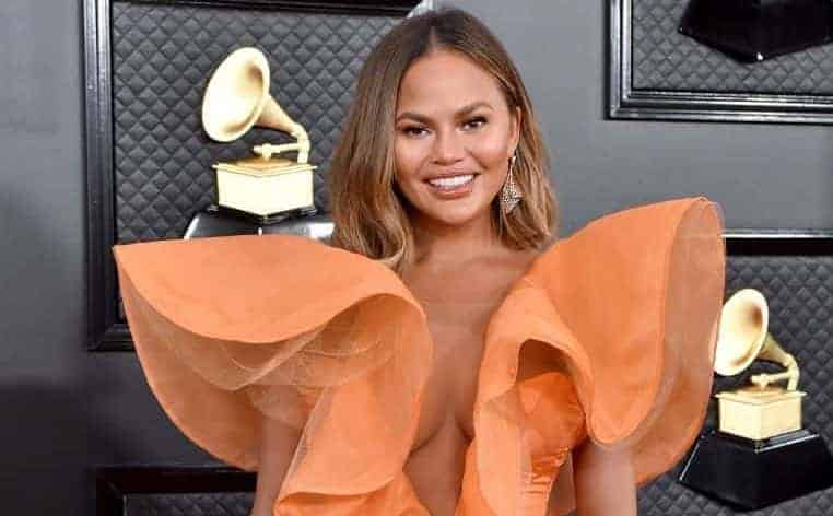 Chrissy Teigen wearing an orange dress
