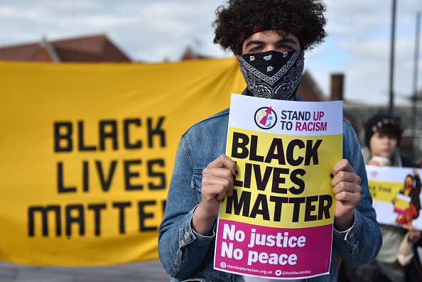 A person holds up a Black Lives Matter placard as they attend a "Take The Knee" event outside Southend Victoria Station on May 25