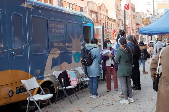 Principal Alice Hom (purple jacket) stands outside Yung Wing School P.S. 124 and a vax van where for the second time this month