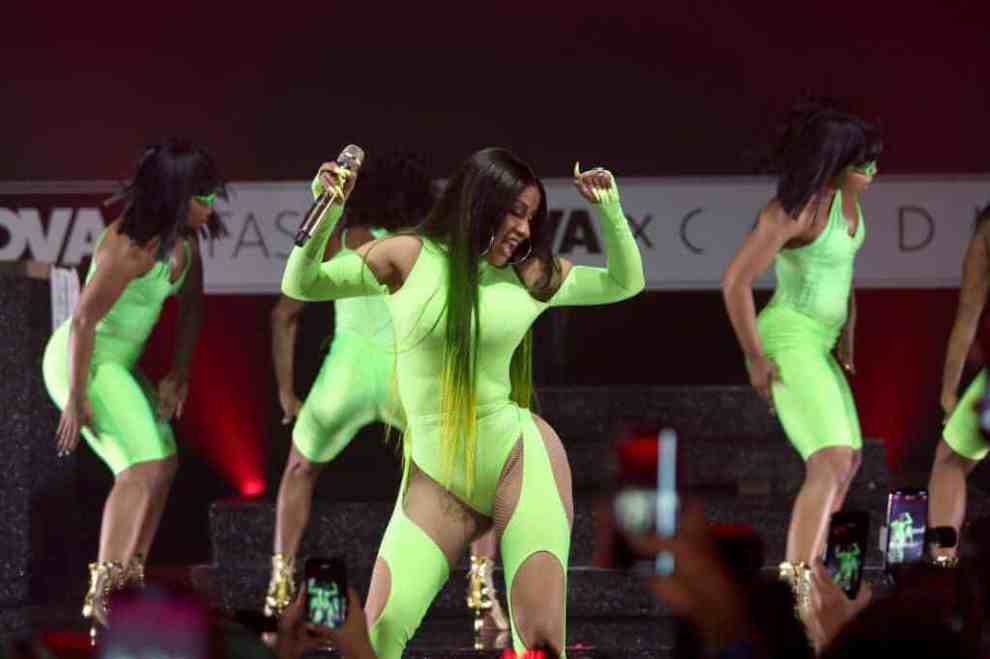 Cardi B wearing a neon green bathing suit on stage