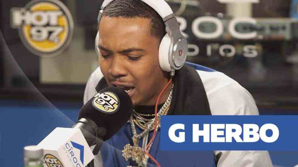 Chicago Rapper G Herbo Rapeeing into Mic Hot97 logo Ciroc logo while wearing Headphones