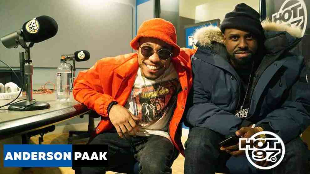 Rapper Anderson Paak with an orange coat and hat