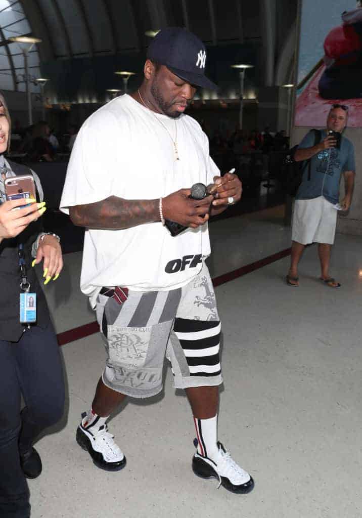 50 Cent walking holding mic and looking down at his phone