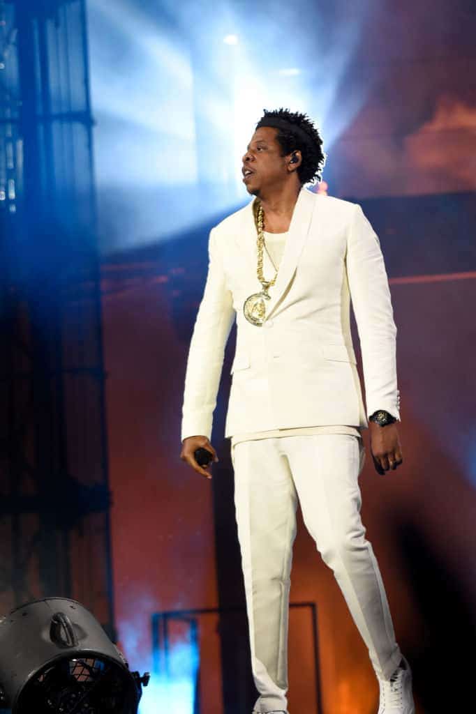 Jay Z wearing all white standing on stage.
