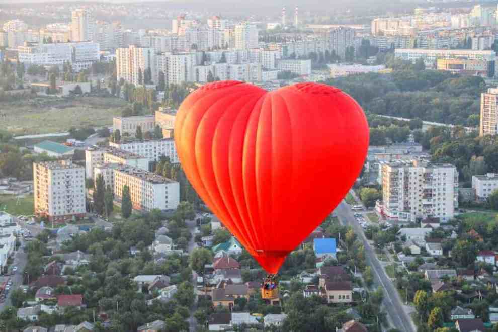 Red heart hot air balloon over city