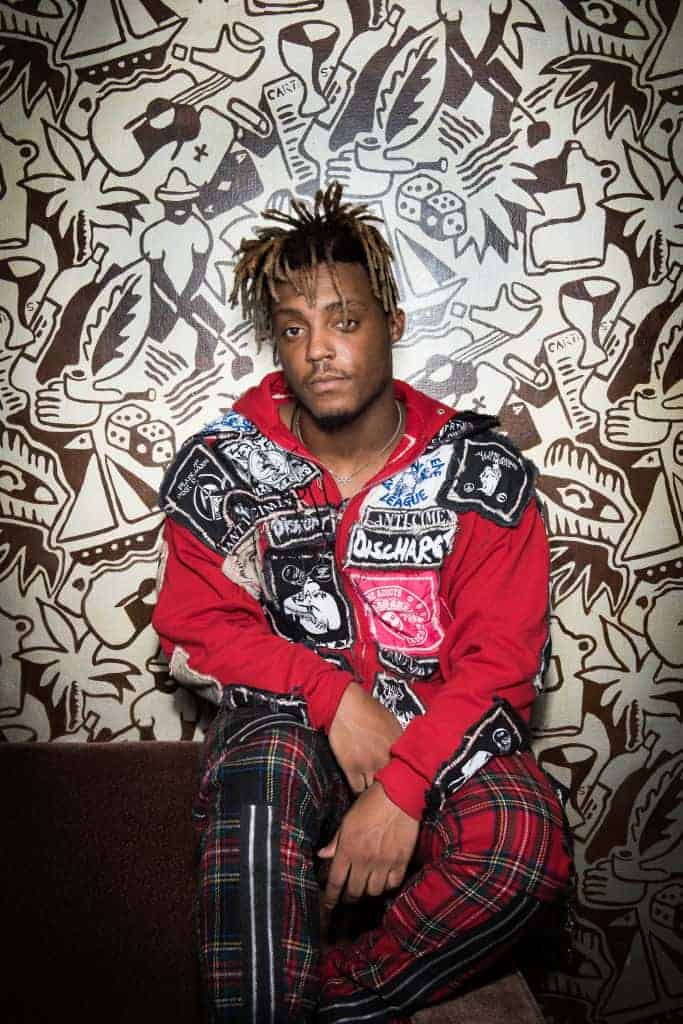 Juice Wrld sitting down wearing a red and blue plaid shirt