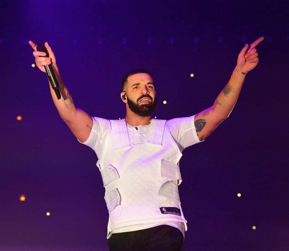 Drake wearing a white vest performing on stage
