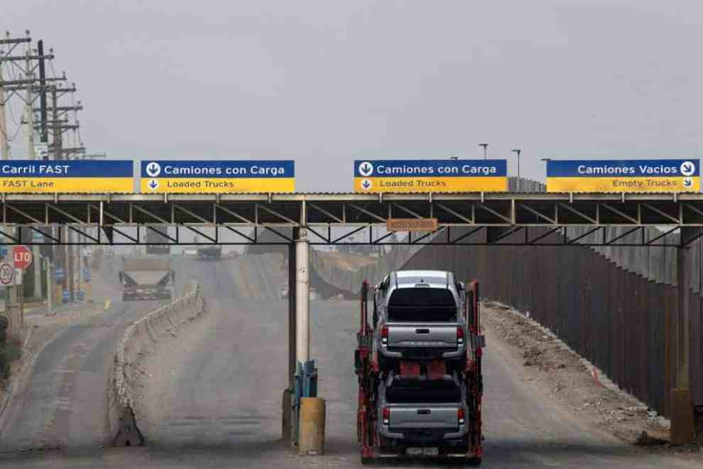 Signs in Spanish of the U.S. Mexican Border with a truck hold two cars.